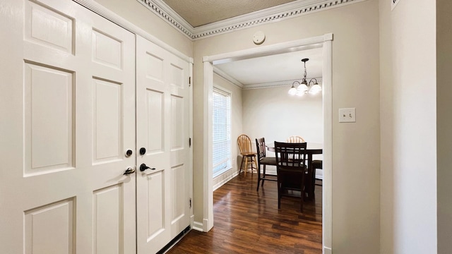 hallway featuring ornamental molding, a textured ceiling, a notable chandelier, and dark hardwood / wood-style floors