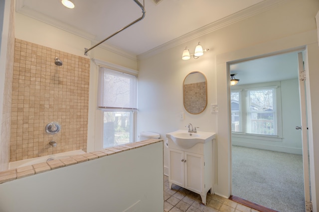 bathroom with ornamental molding, vanity, a wealth of natural light, and tiled shower / bath combo