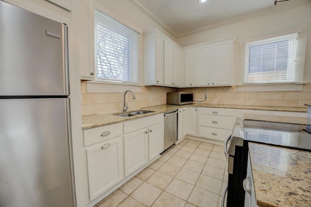 kitchen with appliances with stainless steel finishes, white cabinetry, light stone counters, and sink