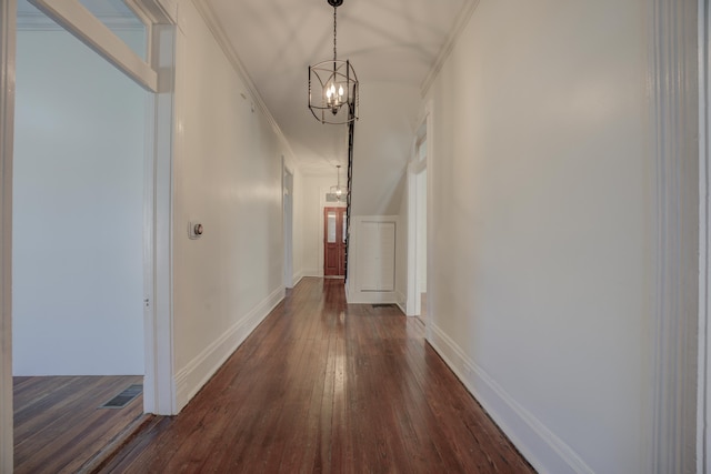 corridor featuring dark hardwood / wood-style flooring, an inviting chandelier, and crown molding