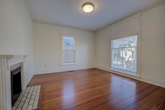 unfurnished living room featuring a fireplace, a healthy amount of sunlight, crown molding, and dark wood-type flooring