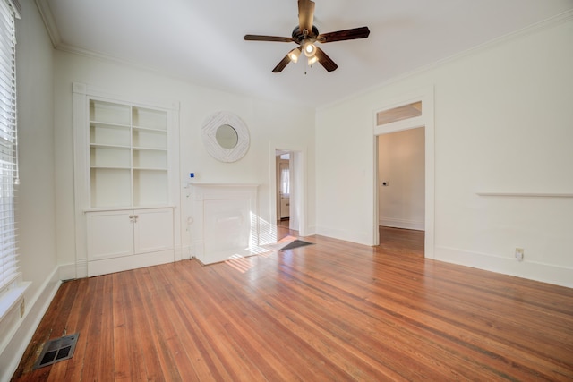 unfurnished living room featuring built in features, ceiling fan, crown molding, and wood-type flooring