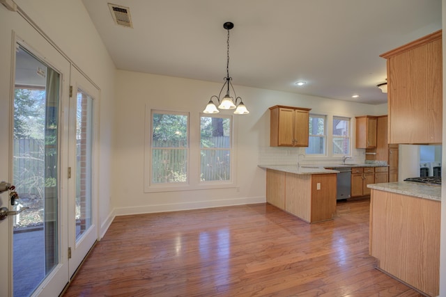 kitchen with kitchen peninsula, dishwasher, decorative light fixtures, a notable chandelier, and backsplash