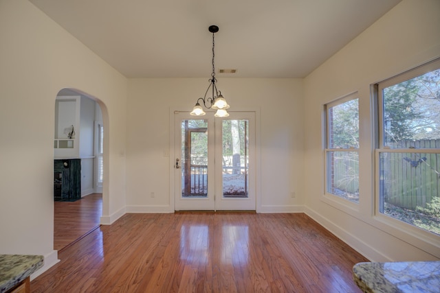 unfurnished dining area featuring a notable chandelier and hardwood / wood-style flooring