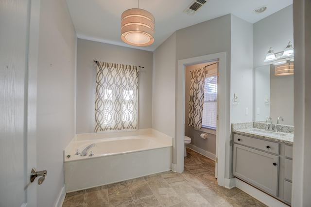 bathroom featuring toilet, a bath, and vanity