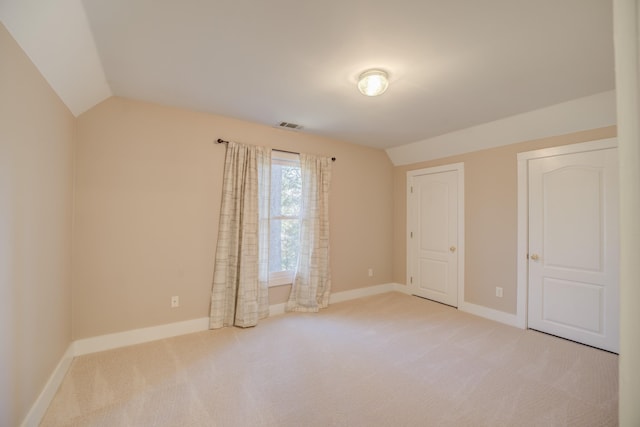 unfurnished bedroom with light carpet and vaulted ceiling