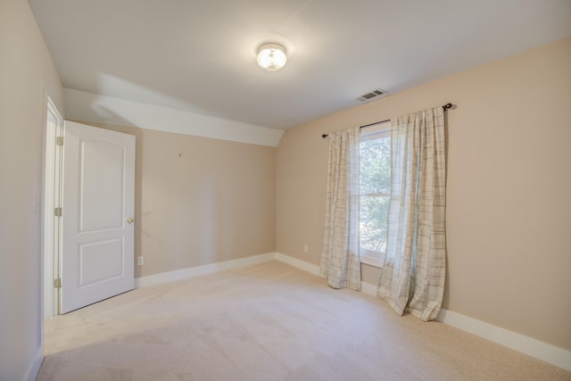 carpeted spare room featuring lofted ceiling