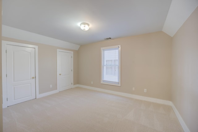 unfurnished bedroom with vaulted ceiling and light carpet