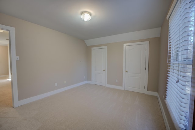 unfurnished bedroom featuring lofted ceiling and light colored carpet