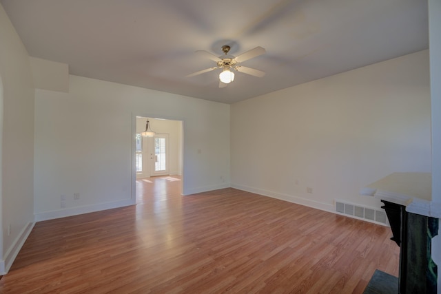 unfurnished living room with ceiling fan, light wood-type flooring, and french doors