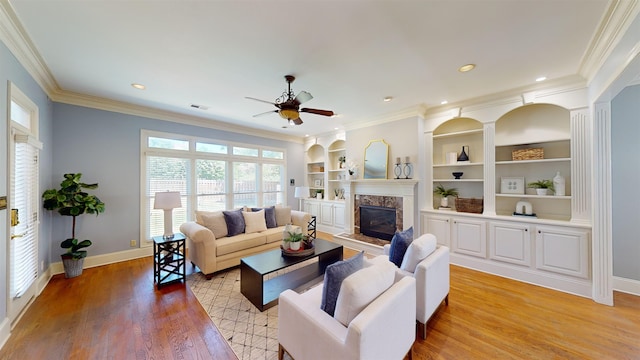 living room with light wood-style floors, a fireplace, baseboards, and crown molding