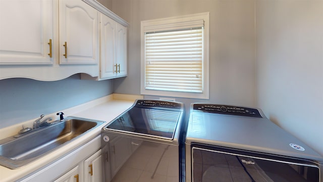 washroom with cabinet space, washer and dryer, and a sink