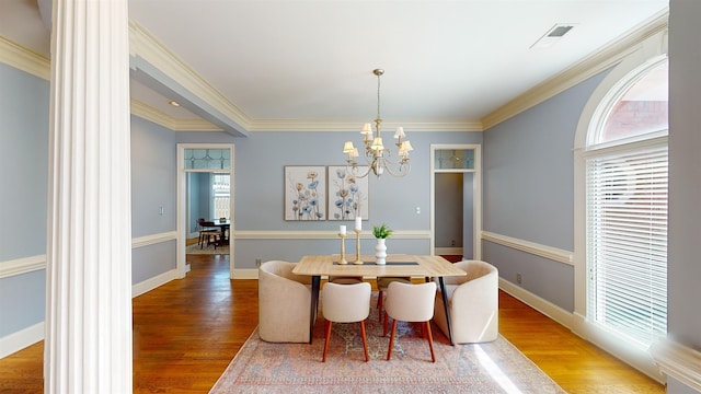 dining space with an inviting chandelier, crown molding, and hardwood / wood-style floors