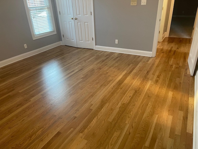 unfurnished room with dark wood-type flooring and baseboards