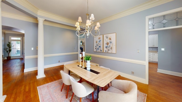 dining area with a chandelier, wood finished floors, baseboards, ornamental molding, and decorative columns