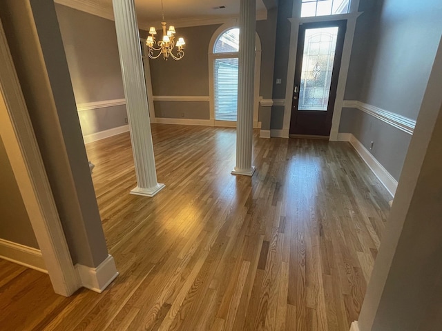 entryway featuring crown molding, ornate columns, and wood finished floors