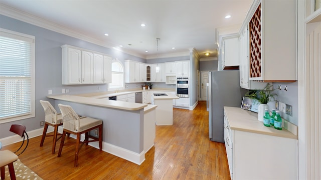 kitchen featuring a peninsula, light wood-style flooring, ornamental molding, and stainless steel appliances