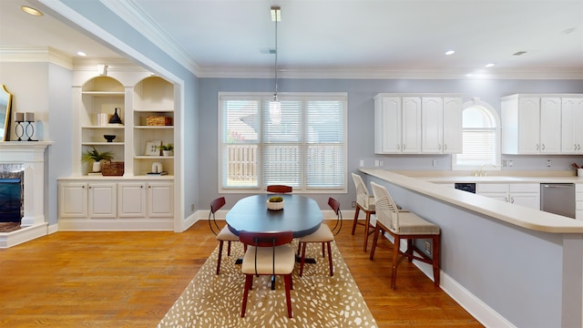 kitchen featuring light wood-style floors, a premium fireplace, white cabinetry, and crown molding