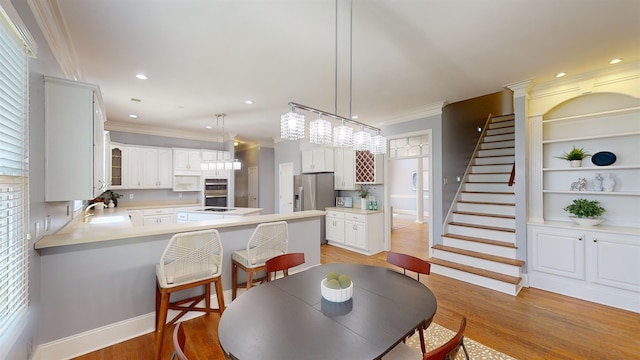 dining space featuring recessed lighting, built in features, stairway, light wood finished floors, and crown molding