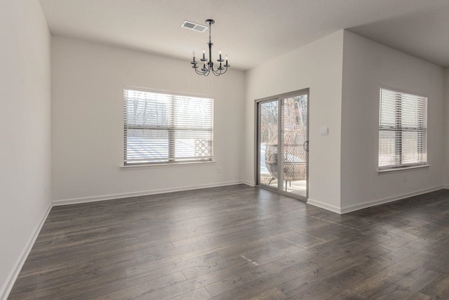 spare room with dark wood-type flooring and a chandelier