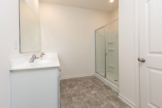 bathroom featuring a shower with door and vanity