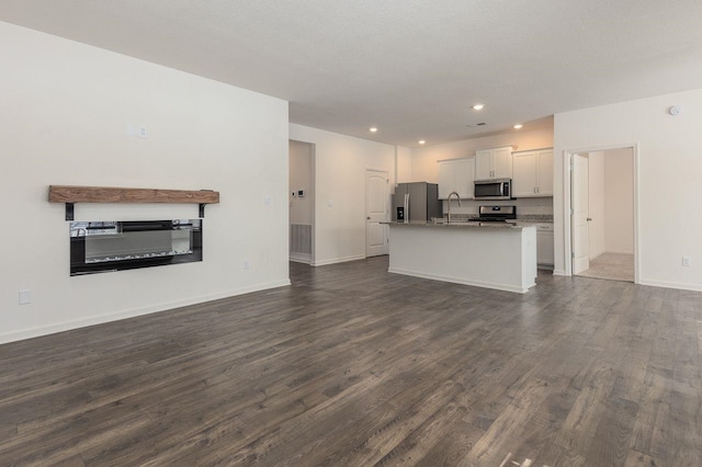 unfurnished living room featuring dark wood-type flooring, a textured ceiling, and sink