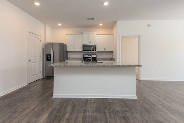 kitchen with white cabinets, dark wood-type flooring, stainless steel appliances, and a center island with sink