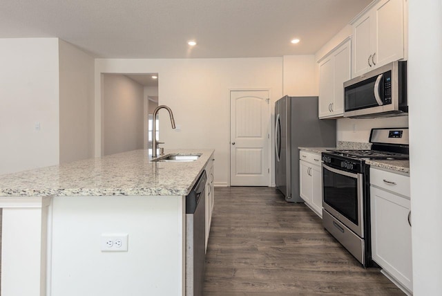 kitchen with a center island with sink, sink, appliances with stainless steel finishes, white cabinets, and light stone counters