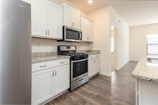 kitchen with light stone counters, white cabinets, appliances with stainless steel finishes, and a healthy amount of sunlight