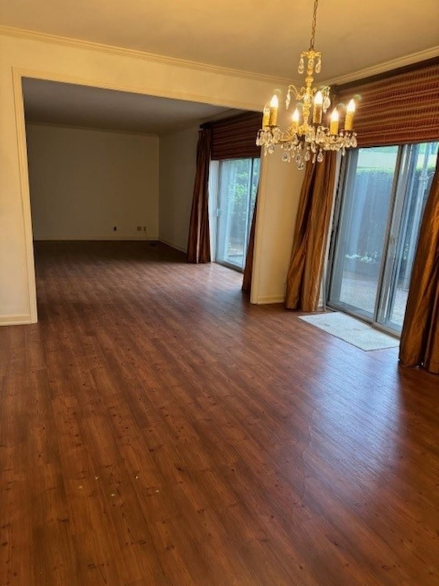 spare room featuring dark hardwood / wood-style flooring, crown molding, and an inviting chandelier