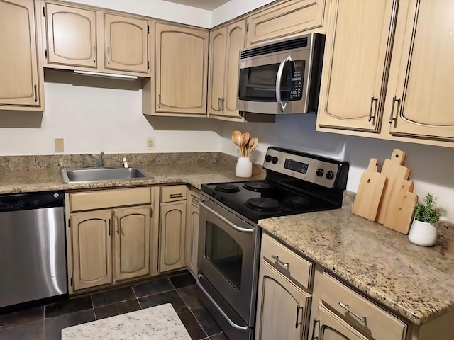 kitchen featuring light brown cabinetry, appliances with stainless steel finishes, sink, and dark tile patterned flooring