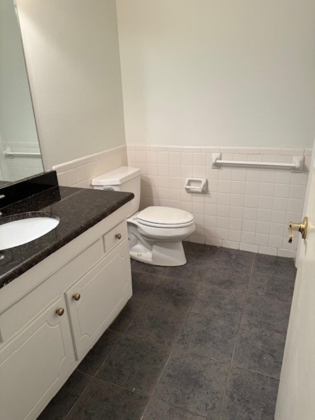 bathroom featuring toilet, tile patterned flooring, tile walls, and vanity