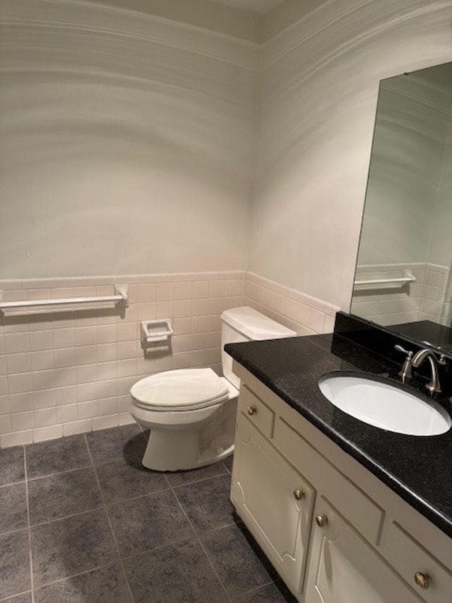 bathroom featuring toilet, tile patterned flooring, tile walls, and vanity