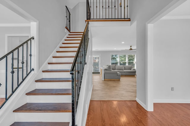 stairway featuring ceiling fan, ornamental molding, and hardwood / wood-style floors