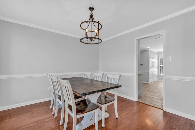 dining space with wood-type flooring, an inviting chandelier, and ornamental molding