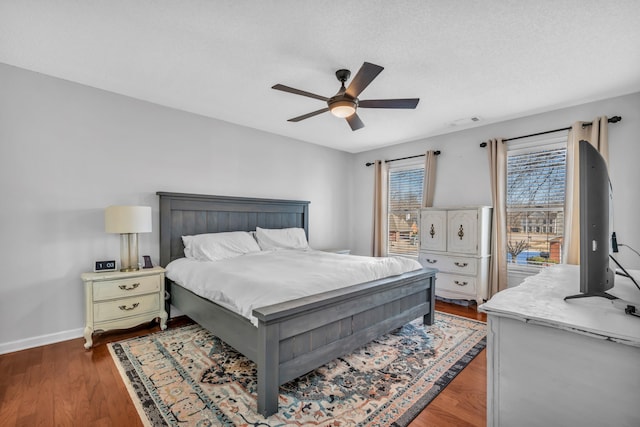 bedroom with ceiling fan, a textured ceiling, and dark hardwood / wood-style flooring