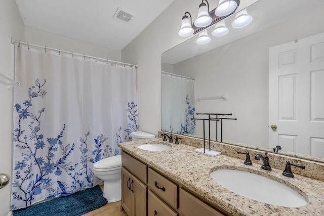 bathroom with toilet, vanity, and tile patterned flooring