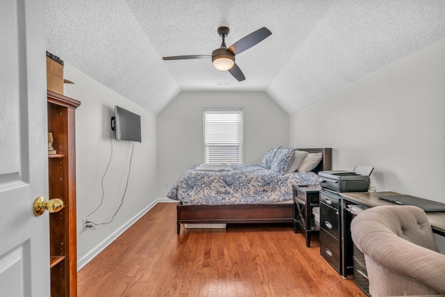 bedroom with a textured ceiling, ceiling fan, lofted ceiling, and hardwood / wood-style floors