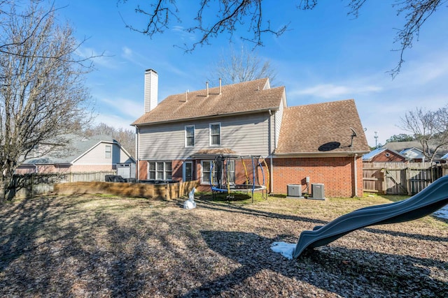 back of property with a playground, a trampoline, and central AC