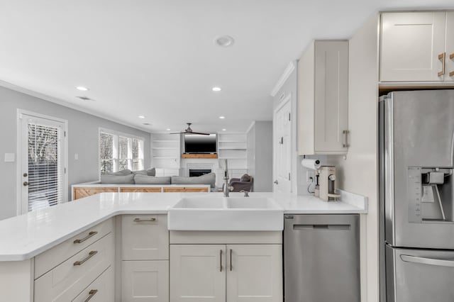 kitchen with appliances with stainless steel finishes, white cabinetry, sink, ornamental molding, and ceiling fan