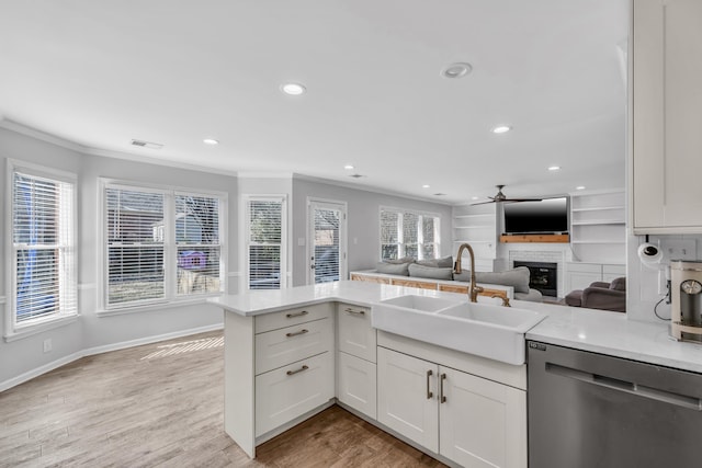 kitchen with stainless steel dishwasher, white cabinets, kitchen peninsula, and sink