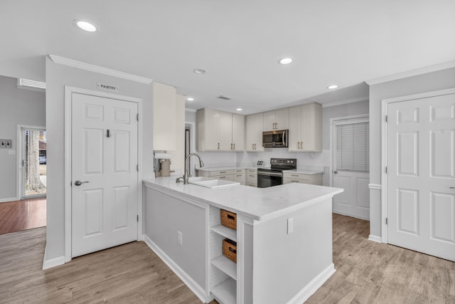 kitchen with kitchen peninsula, appliances with stainless steel finishes, sink, and light hardwood / wood-style floors