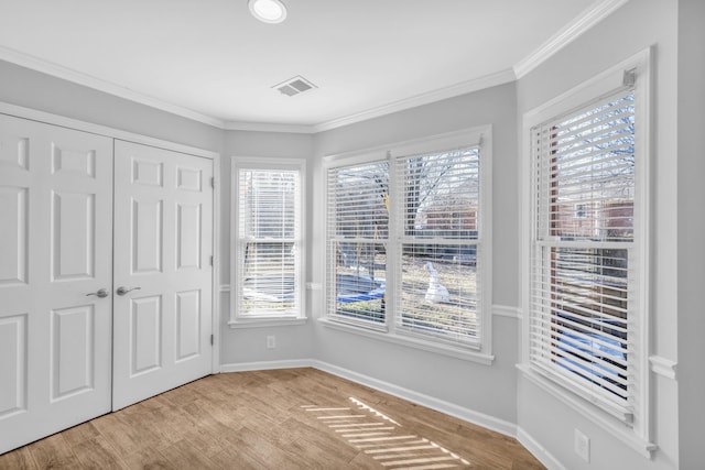 unfurnished bedroom with light wood-type flooring, a closet, and crown molding