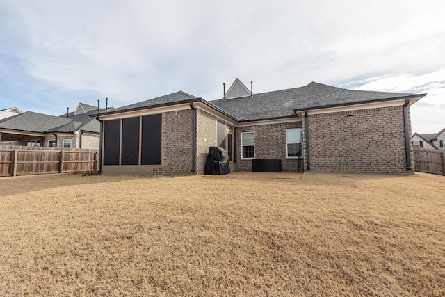 rear view of house featuring a lawn and a sunroom