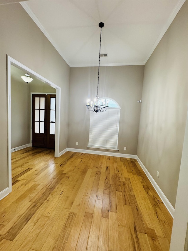 unfurnished dining area with an inviting chandelier, crown molding, and light hardwood / wood-style flooring