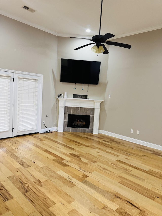 unfurnished living room with ceiling fan, crown molding, light hardwood / wood-style floors, and a tiled fireplace