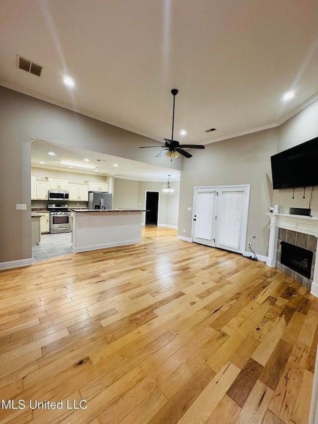 unfurnished living room featuring ceiling fan, light hardwood / wood-style flooring, crown molding, and a fireplace