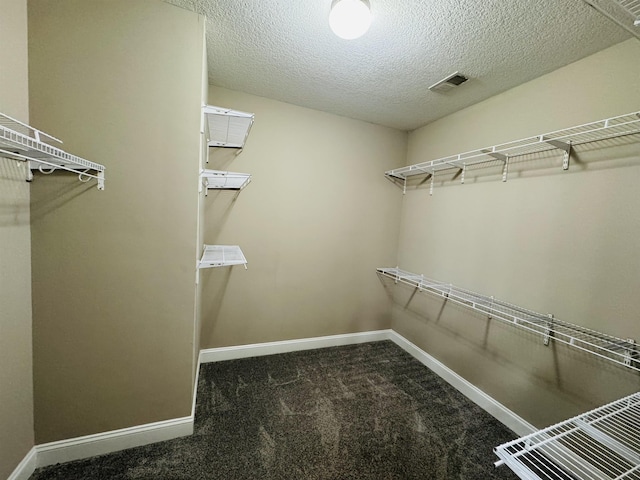 walk in closet featuring dark colored carpet