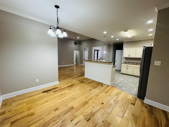 kitchen featuring ceiling fan with notable chandelier, white cabinetry, stainless steel refrigerator, ornamental molding, and light wood-type flooring