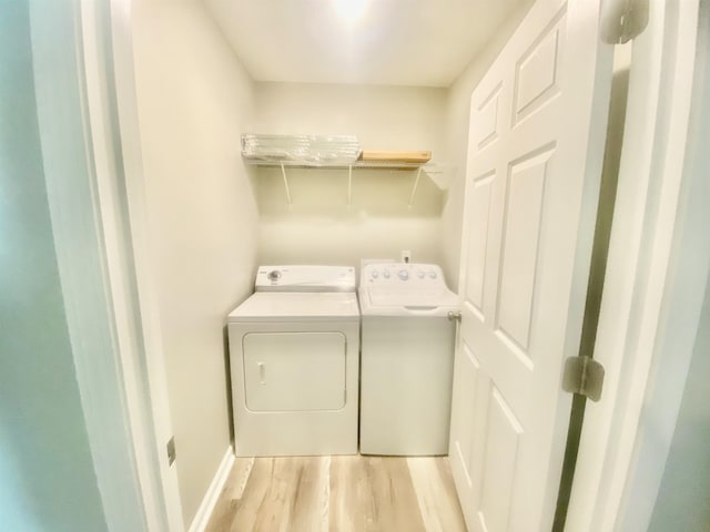 laundry area with washing machine and clothes dryer and light hardwood / wood-style flooring